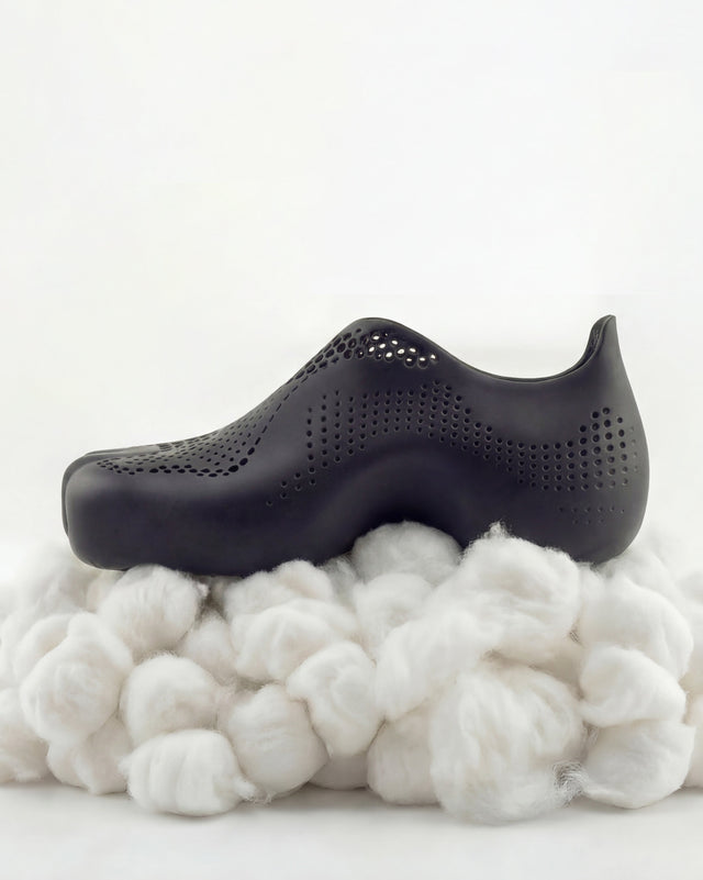 Black shoe on a pile of cotton with a white background
