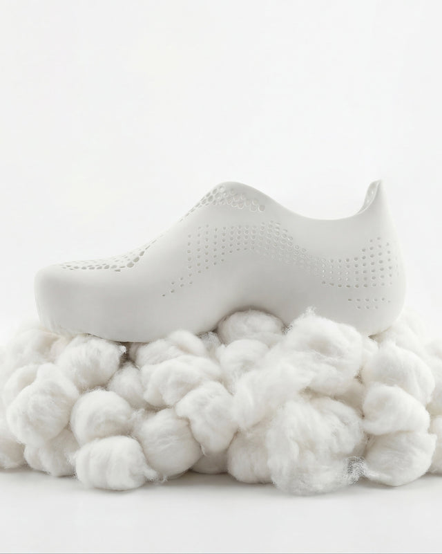 White baby shoe on a bed of cotton with a white background
